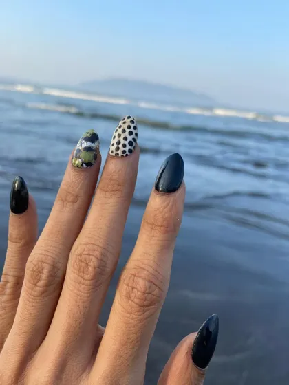 Party nails ready for the beach. This edgy look features glossy black polish on stiletto nails, with accent designs including leopard print and camo glitter.