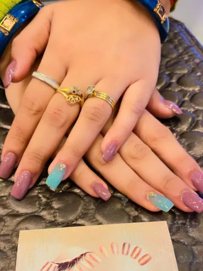 A chic and modern set of square nails. The design features a mix of solid mauve and light blue accent nails with tiny crystal details.