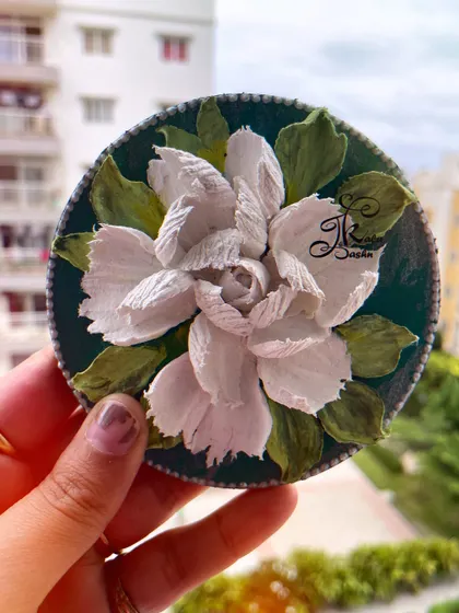 The white gardenia fridge magnet held in hand to show its size. It's a perfect little piece of art to brighten up a kitchen.
