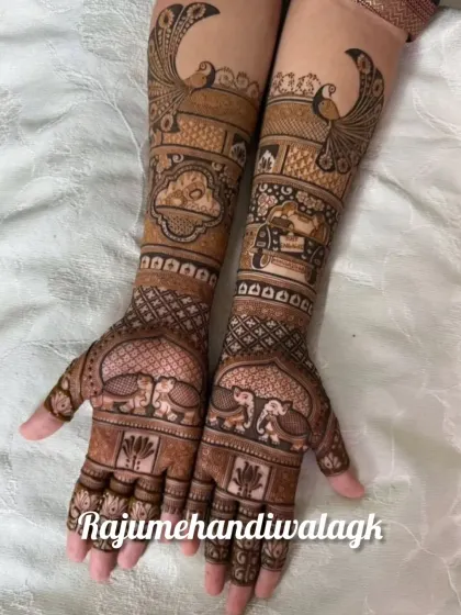 A beautiful bridal mehendi featuring peacocks and elephants, symbols of grace and royalty. The design extends up the arm in neat, patterned bands.