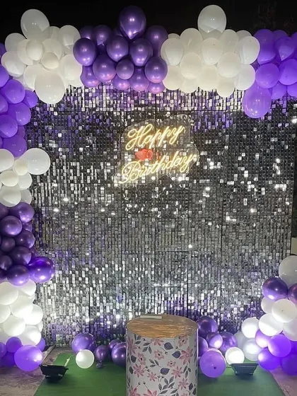A purple and white balloon arch over a sequin backdrop, perfect for an outdoor or terrace party.