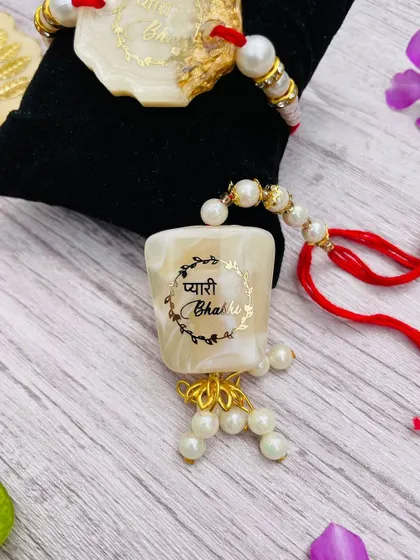 A close-up of the "Pyari Bhabhi" lumba rakhi, which matches the brother's rakhi in style and color.