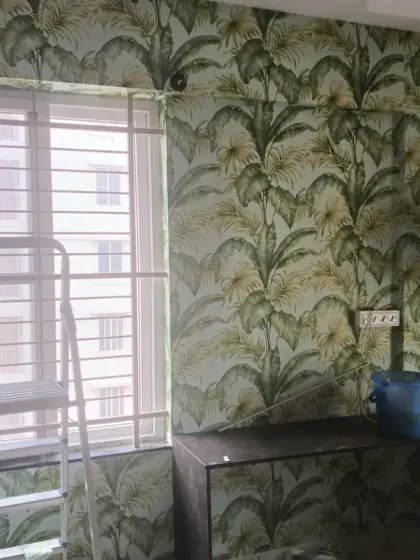 A green tropical leaf wallpaper installed in a kitchen or utility area. The pattern is carefully cut around the window and countertop.