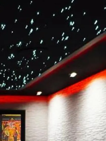 Another view of a custom home cinema, highlighting the layered lighting design with spotlights and recessed cove lighting. This level of control allows the owner to set the perfect mood for any occasion.