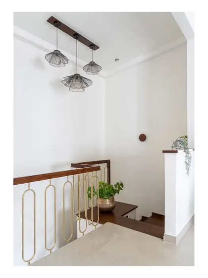 The upper landing of the staircase, featuring a chic dull matt golden railing and a cluster of delicate pendant lights, continuing the home's blend of modern and vintage aesthetics.