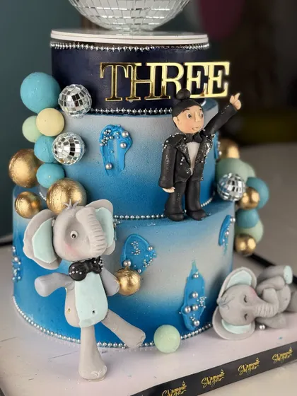 Standing tall and majestic. This elephant-themed cake is a sweet celebration of grandeur, featuring a disco ball tier and adorable fondant elephants for a unique birthday party.