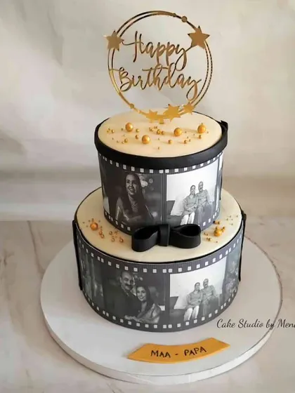 A beautiful monochrome two-tier cake for a combined parents' birthday. The edible photo reels wrap around each tier, showcasing cherished family moments in a classic black and white style.