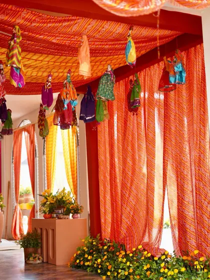 An authentic and colorful entrance for a Rajasthani-themed Haldi. We used 'lehariya' print drapes and hung traditional puppets from the ceiling to create a festive and welcoming entryway.