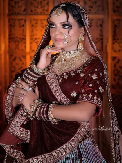 A three-quarter portrait of the bride, highlighting the rich texture of the velvet and the intricate silver embroidery on her lehenga and dupatta.