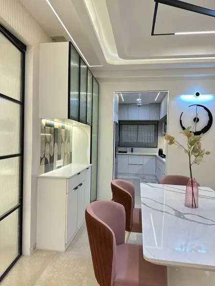 A view from the dining table towards the crockery unit and kitchen entrance. The cohesive design, with its clean lines and modern finishes, creates a seamless flow between spaces.