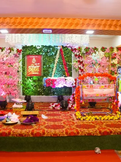The stage decoration for a naming ceremony, featuring a floral backdrop and a traditional cradle.