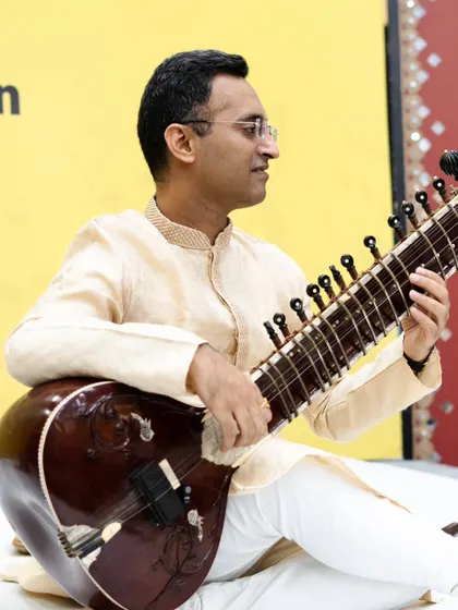 Playing a composition at the SPIC MACAY event, with a microphone setup suitable for school auditoriums.