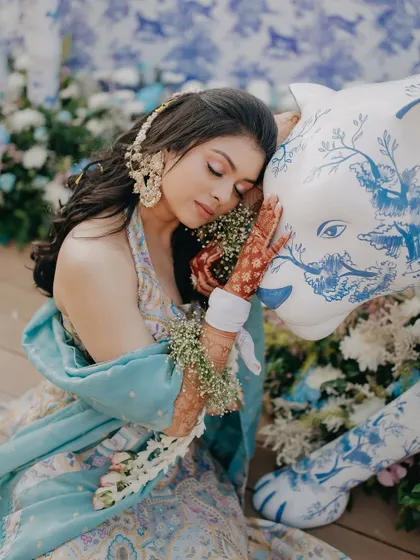 A beautiful, serene portrait of the bride Radhika during her Haldi. Her floral jewelry and the artistic decor element create a stunning and unique image.