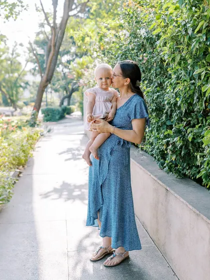 A mother holding her baby girl on a sunny sidewalk. A simple, everyday moment made beautiful.