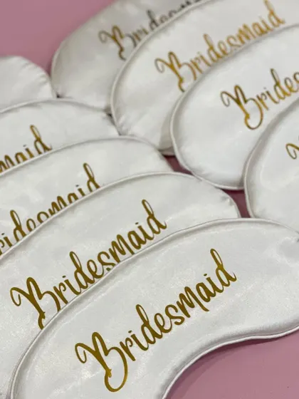 Simple and elegant, these white satin eye masks with "Bridesmaid" written in gold script are a lovely and practical favor for the entire bridal party.