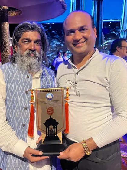 A photo with Shri Nitin Desai after being honoured at his event. I am holding the memento he presented to me.