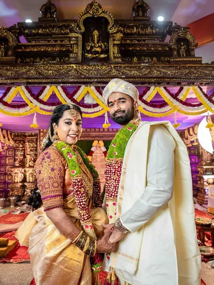 A grand and beautiful shot of the bride and groom at the mandapam. The makeup is designed to look stunning in the grand setting of a wedding.