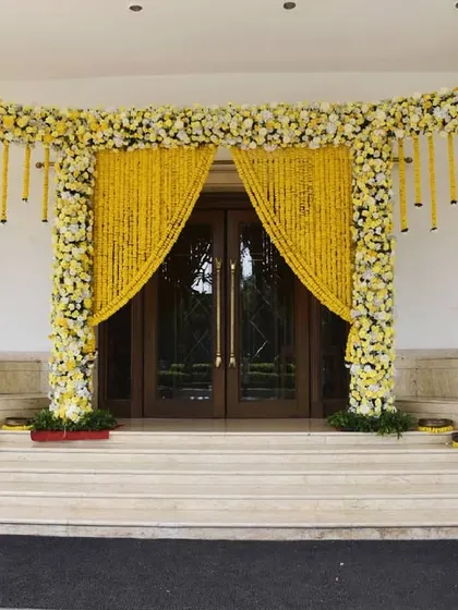 A full view of the grand marigold entrance, combining traditional flower curtains with contemporary floral-wrapped pillars.