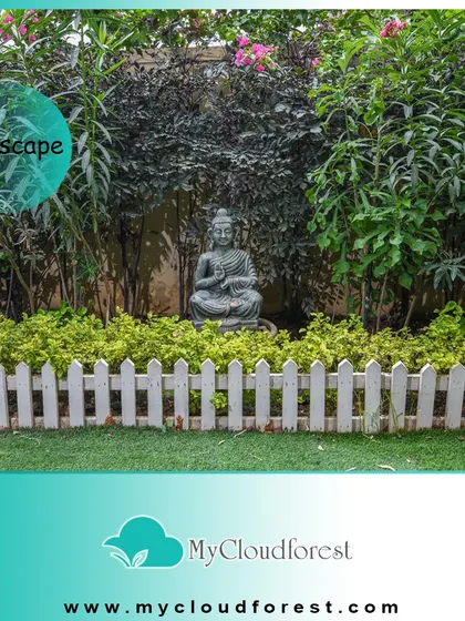 A simple Buddha statue placed within a dense garden bed can create a powerful focal point. Here, it is framed by a classic white picket fence and lush foliage, adding a touch of tranquility to a traditional garden layout.