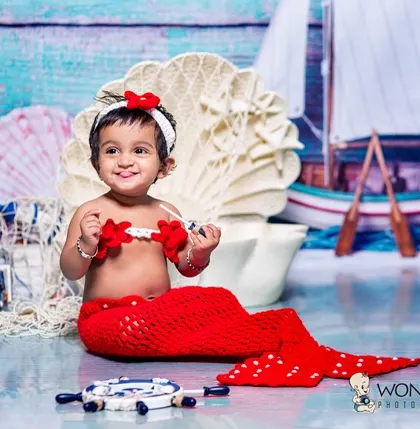 A beautiful mermaid portrait against a nautical backdrop. I use crocheted outfits and themed props like shells and sailboats to create an enchanting underwater world for your child.