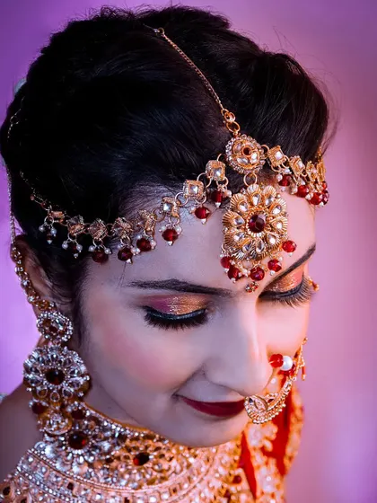 A beautiful close-up of the bride's face, focusing on her dramatic eye makeup and traditional jewelry.