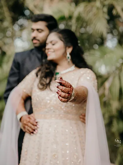A creative shot focusing on the bride's mehendi and engagement ring, with the couple sharing a soft-focus moment in the background. It's all about the details.