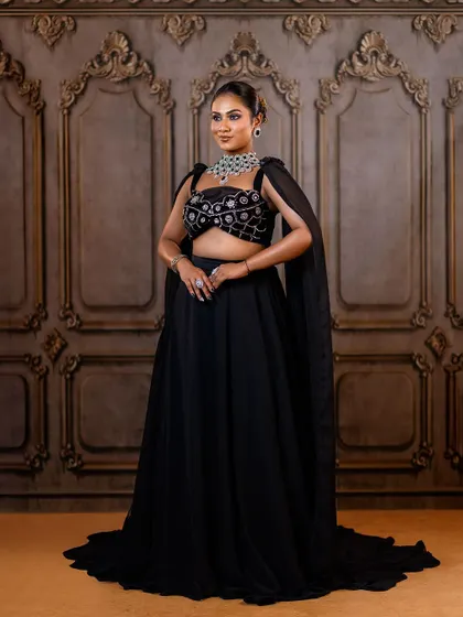 A powerful, full-length shot of a black reception lehenga. The cape-like sleeves and intricate silver embroidery create a look that is both elegant and commanding.