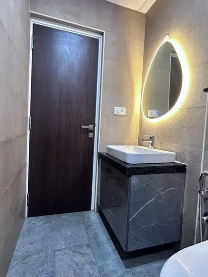 A minimalist bathroom with a marble-finish vanity and a simple, elegant backlit oval mirror. This design proves that even functional spaces can be beautiful.
