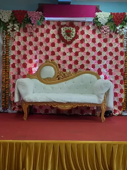 Another view of an engagement stage with a floral wall backdrop. This setup uses a mix of marigold garlands and drapes for a more traditional Indian wedding feel.