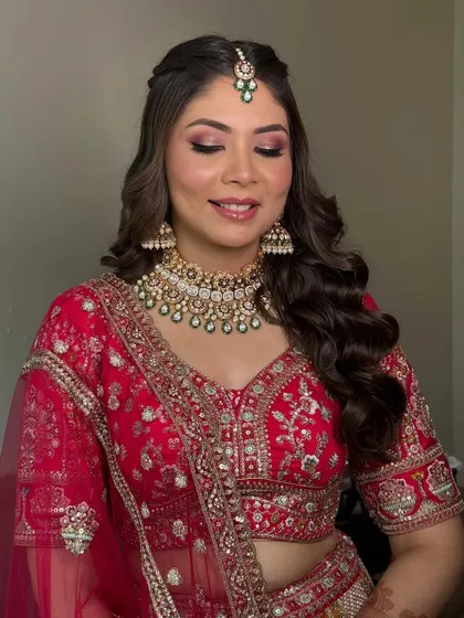 A soft, dreamy expression from the bride. The warm, shimmery eyeshadow is perfectly blended, complementing her red lehenga and gold jewellery for a cohesive and beautiful look.