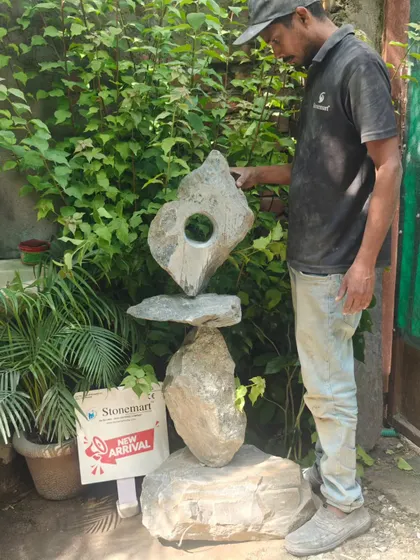 An artisan stands beside the 4-foot "Balance of Life" sculpture, providing a sense of its scale. This piece is crafted to be a striking focal point in any modern garden.