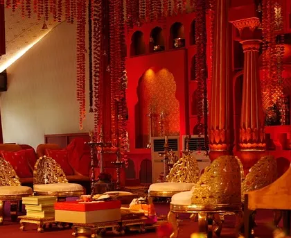 The seating area for the family within the 'Lal Bagh' mandap, featuring ornate silver and gold chairs against a backdrop of rich red.