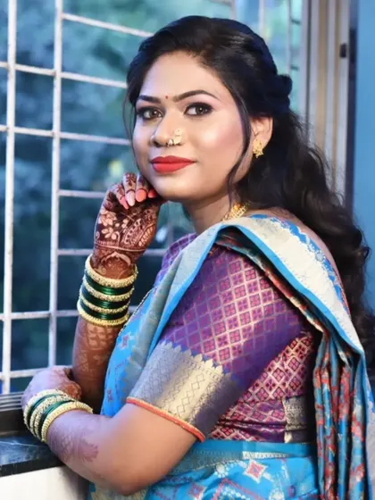 The final look. This makeup features a soft, smokey eye and a classic red lip, perfectly complementing her blue and purple silk saree for a traditional yet fresh appearance.