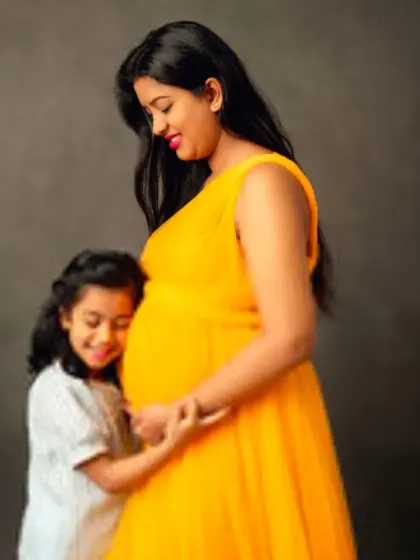 A sweet moment between a mother and her daughter, both excited for the new baby. The mom-to-be is wearing a vibrant yellow flowing gown.