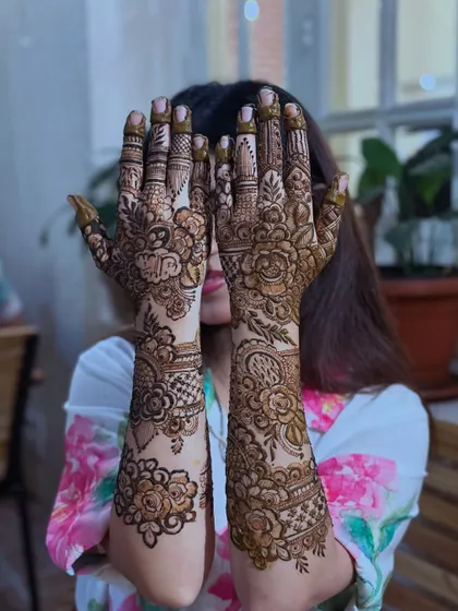 The classic "peek-a-boo" pose with a stunning floral henna design. It's a playful way to show off the intricate work.