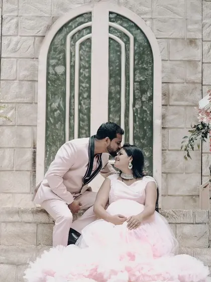A tender moment on a grand staircase, with the father-to-be kissing his partner's forehead.