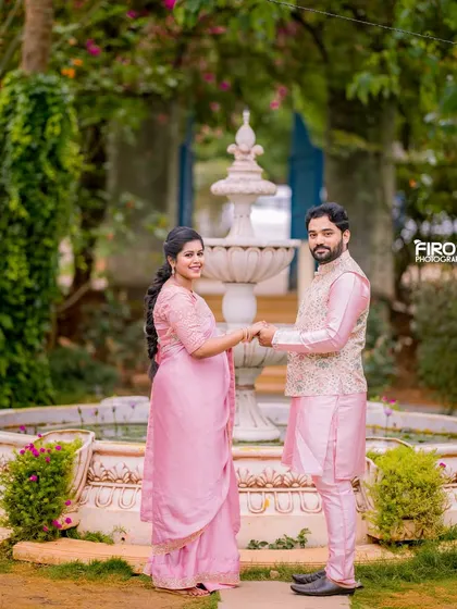 This couple, dressed in elegant pink traditional wear, holds hands in front of a classic water fountain. It’s a timeless and romantic setting for a pre-wedding or maternity photoshoot.