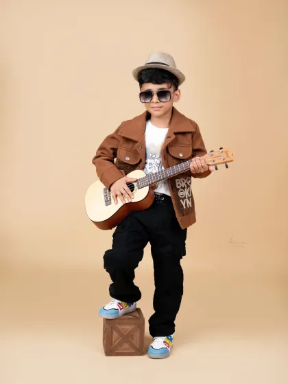 A little rockstar in the making! This cool dude is strumming his guitar during his fun and stylish photoshoot.