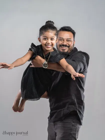 A father holds his daughter, who is flying like an airplane. This playful studio shot is full of energy and captures the fun-loving bond they share.