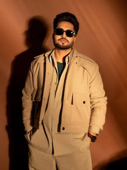 A medium shot that highlights the layers of his outfit and his confident pose.