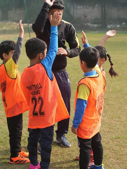 A coach high-fiving young players. This personalized approach helps build confidence and enhances skills.