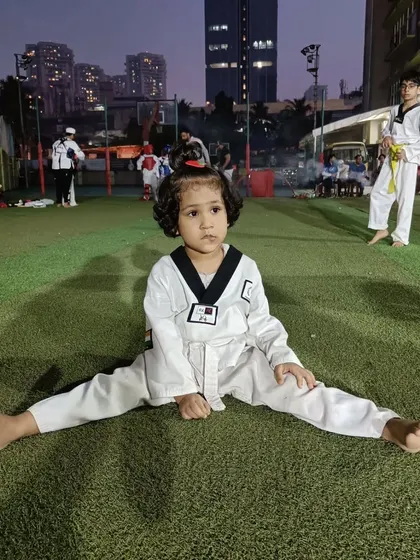 A quiet moment of focus. Even during a busy class, this young student maintains her stretching posture, demonstrating the discipline we instill from day one.