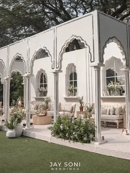The full view of the stunning ivory lounge pavilion, an open-air structure that feels both grand and intimate, set on a lush green lawn.