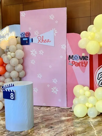 Lights, camera, action. Rhea's movie-themed party featured a fun popcorn box prop, a director's clapperboard, and a 'Happy Birthday' neon sign for a Hollywood-style celebration.