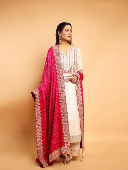 The lovely Hina Khan in a classic ivory and pink suit. The heavily embroidered bandhani dupatta adds a pop of color and traditional elegance, making it perfect for any grand celebration.
