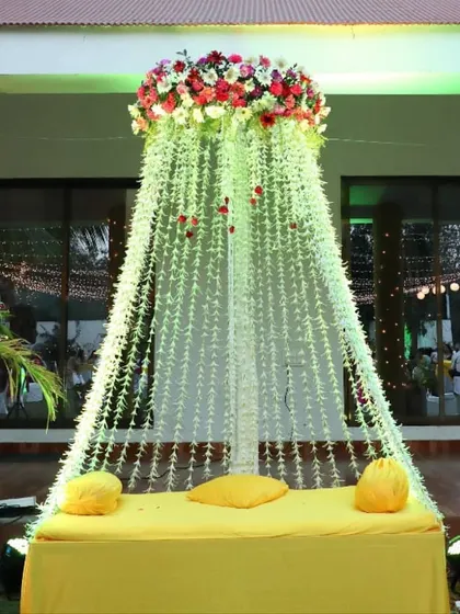 A beautiful bridal seat for a Mehendi or Haldi ceremony. We created a canopy of falling white flowers topped with a crown of colorful blooms, making the bride the center of attention.