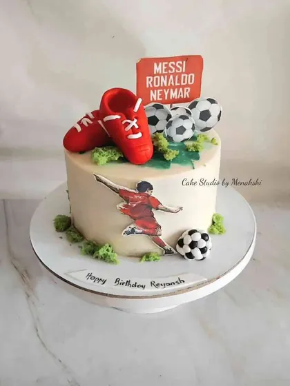 A cake for a football fan, featuring edible images of their favorite players, soccer balls, and bright red cleats on top.