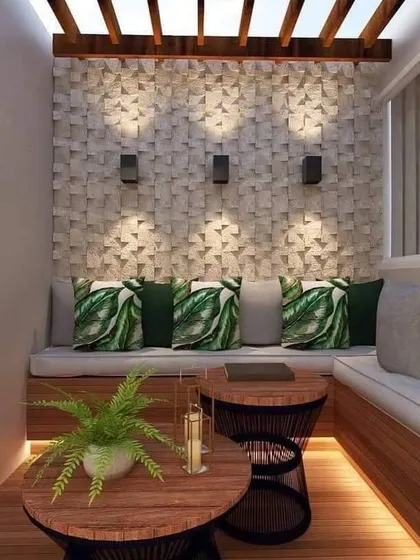 A cozy and private patio nook with built-in wooden seating and a textured stone accent wall. The overhead wooden beams provide partial shade, and the lighting creates a warm glow.