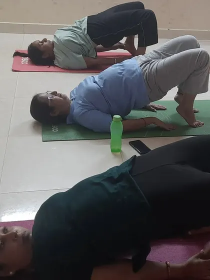 A women's yoga class working on Setu Bandhasana, or Bridge Pose. This pose strengthens the back, glutes, and hamstrings, and is also known to open the Anahata or heart chakra.
