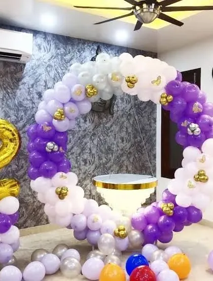 A circular balloon frame decorated with purple, white, and gold balloons. A large gold foil number '2' marks the milestone.